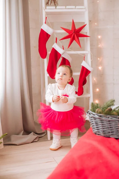ガーランドと松葉の枕の間で クリスマスのために装飾された部屋の大きなベッドの上の風通しの良いドレスで1歳未満の少女 クリスマス気分 子供とクリスマス — ストック写真