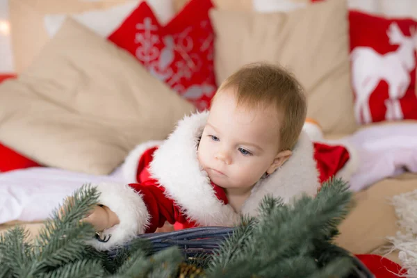 一个一岁以下的小女孩 穿着圣诞老人的衣服 躺在装饰着圣诞节的房间里的一张大床上 睡在花环和松针的枕头里 圣诞气氛 儿童与圣诞节 — 图库照片