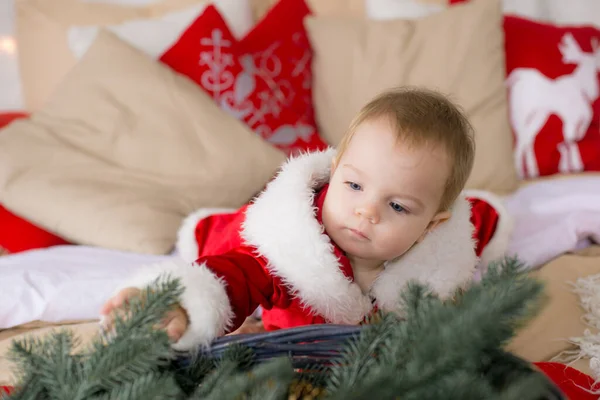 一个一岁以下的小女孩 穿着圣诞老人的衣服 躺在装饰着圣诞节的房间里的一张大床上 睡在花环和松针的枕头里 圣诞气氛 儿童与圣诞节 — 图库照片