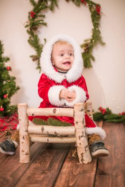 Noel için dekore edilmiş bir odada Noel Baba gibi giyinmiş şirin bir çocuk. Noel ve çocuklar