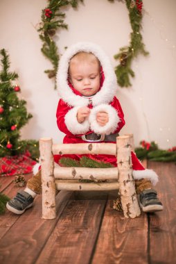 Noel için dekore edilmiş bir odada Noel Baba gibi giyinmiş şirin bir çocuk. Noel ve çocuklar