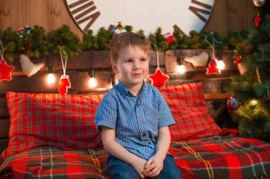 Noel ağacı yakınında Noel için dekore edilmiş bir odada mavi gömlekli yakışıklı bir çocuk. Aile Noel 'i Noel havası