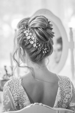 Yatak odasındaki yatak odasının yanında inci ve kristallerle düğün saç stili olan genç ve güzel bir gelin. düğün sabahı