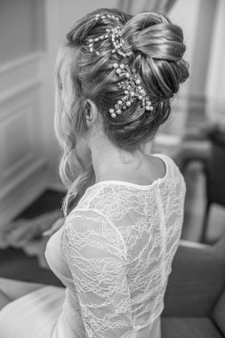 Yatak odasındaki yatak odasının yanında inci ve kristallerle düğün saç stili olan genç ve güzel bir gelin. düğün sabahı