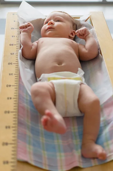 Cute baby lying in height meter — Stock Photo, Image