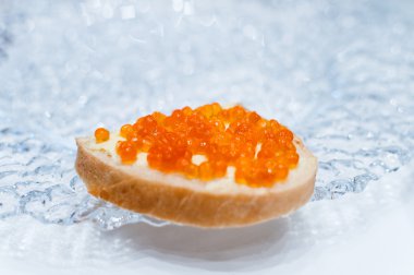 bir cam tabakta somon kırmızı havyar ile sandviç