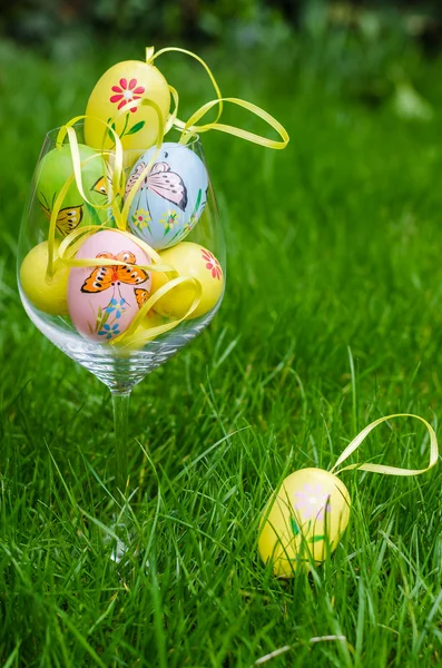 Painted easter eggs in glass on green grass — Stock fotografie