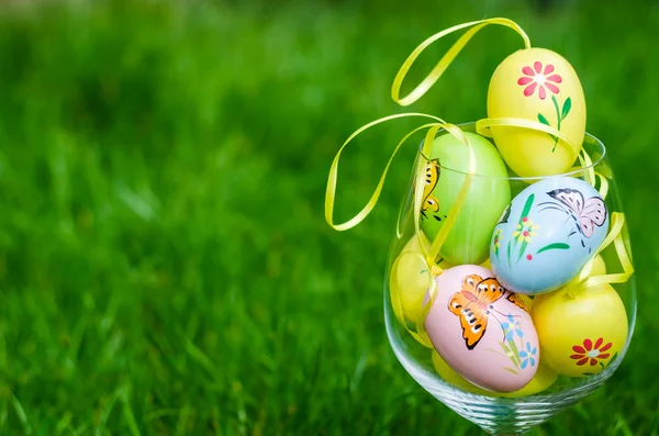 Painted easter eggs in glass on green grass — Zdjęcie stockowe