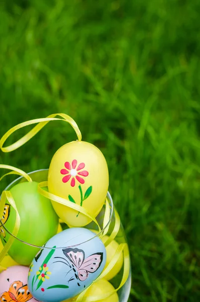 Painted easter eggs in glass on green grass — Zdjęcie stockowe