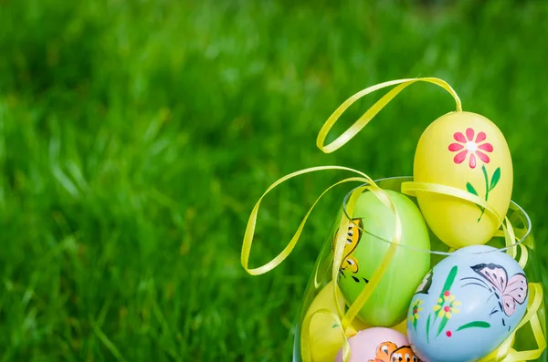 Painted easter eggs in glass on green grass — Stock Photo, Image