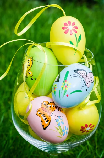 Painted easter eggs in glass on green grass — Zdjęcie stockowe