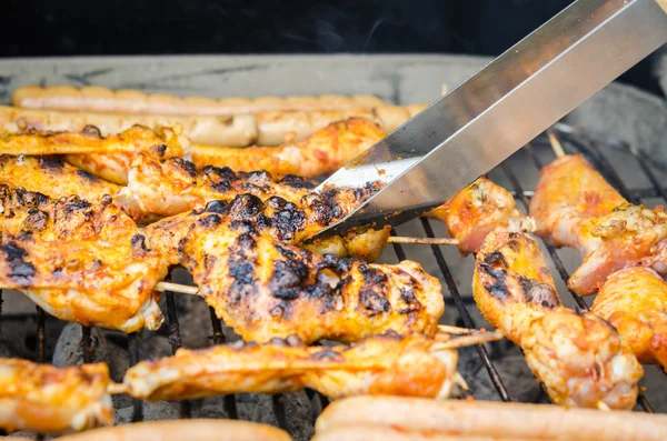 Sausages and chicken wings on smoking grill barbeque — Stock Photo, Image