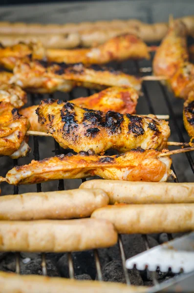 Sausages and chicken wings on smoking grill barbeque — Stock Photo, Image