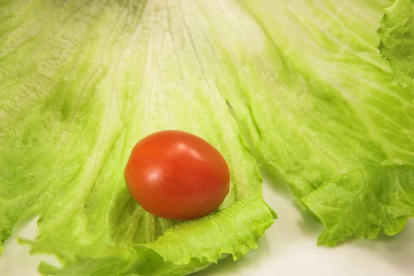 Cherry tomato on a leaf of lettuce — Stock Photo, Image