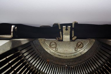 A Closeup image of the typebars and ribbon of an old style typewriter and paper
