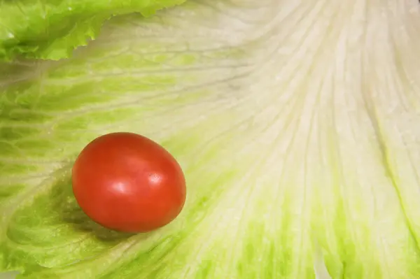 Cherry tomato on a leaf of lettuce — Stock Photo, Image
