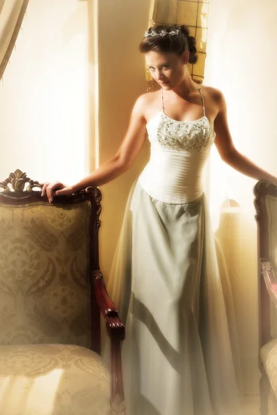 Magro bela mulher adulta com longos cabelos castanhos, encaracolados vestindo luxuoso vestido de noiva de seda — Fotografia de Stock