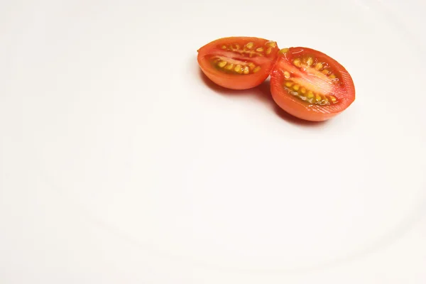 Um tomate cereja em um prato branco — Fotografia de Stock