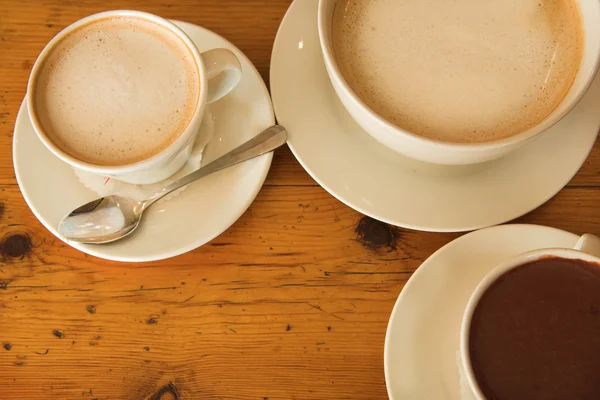 Horké čokolády a kávy na dřevěný stůl — Stock fotografie