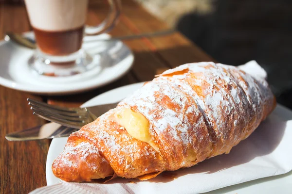 Kuppi kahvia ja tuoretta kermaa croissant puinen pöytä — kuvapankkivalokuva