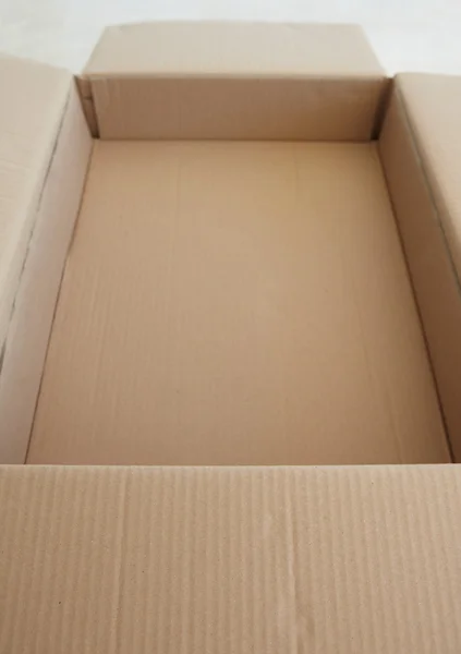 Lege bruin kartonnen doos open staande op een tegelvloer — Stockfoto