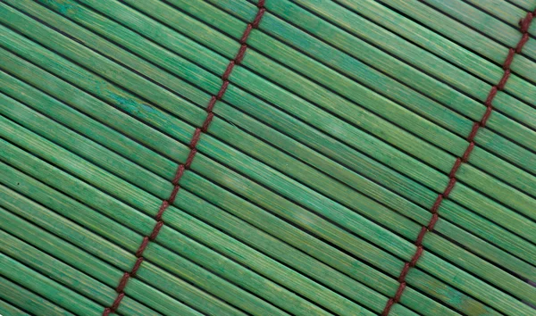 Rough textured green bamboo placemat with brown stitching. — Stock Photo, Image