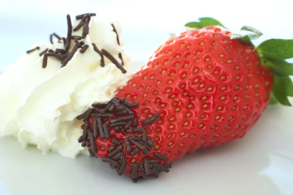 Fragola fresca matura con piccole spruzzate di cioccolato servita come dessert con una guarnizione laterale di crema — Foto Stock