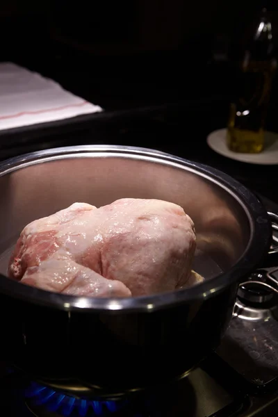 Uncooked chicken in a stainless steel pot on a gas stove lit — Stock Photo, Image