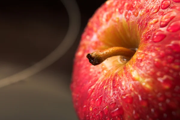 Rött äpple med droppar vatten på en svart glas bakgrund — Stockfoto