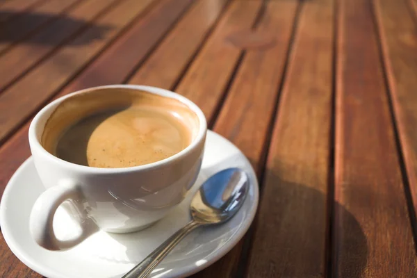 A cup of coffee on a wooden table in an outdoor cafe