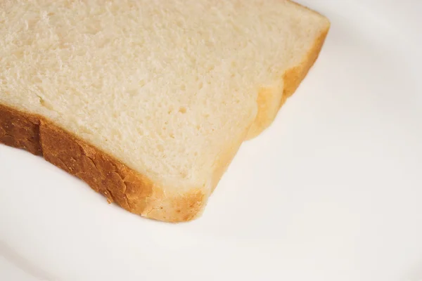 Uma fatia de pão branco em um prato branco . — Fotografia de Stock