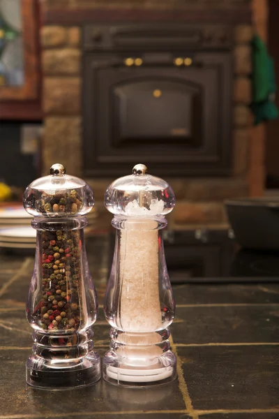 Salt e pimenta shaker em uma superfície de trabalho dentro de uma cozinha — Fotografia de Stock