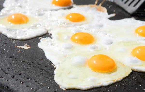 Uova fresche che vengono fritte lato soleggiato su una grande padella — Foto Stock