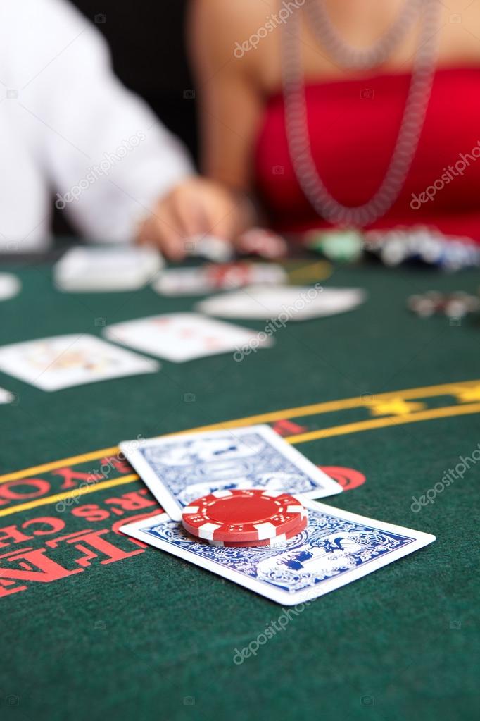 playing cards, chips and players gambling around a green felt poker table