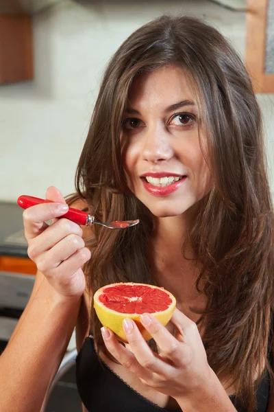 Sexy jonge volwassen brunette vrouw in zwarte lingerie eten een grapefruit — Stockfoto