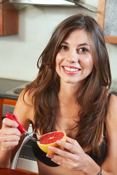 Sexy jonge volwassen brunette vrouw in zwarte lingerie eten een grapefruit — Stockfoto