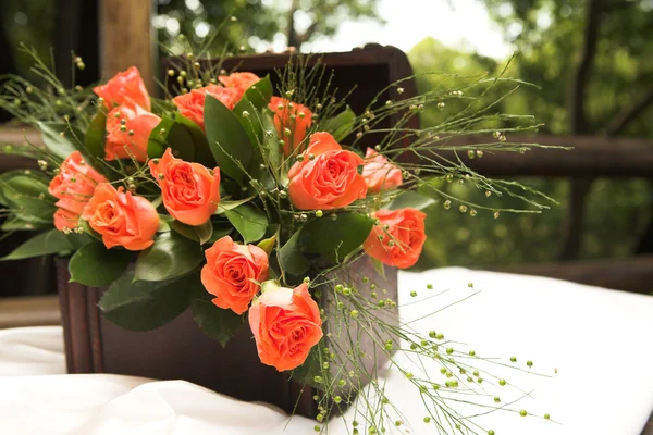 Un arreglo floral con rosas rojas y hojas verdes — Foto de Stock