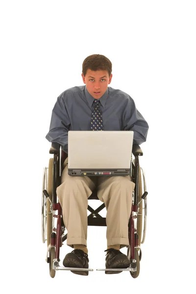 Człowiek pracuje na laptopie siedząc na wózku inwalidzkim. — Zdjęcie stockowe