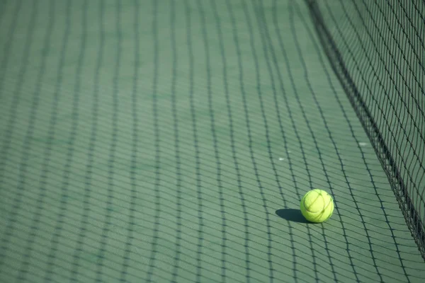 Pelota de tenis amarillo en una cancha de tenis verde — Foto de Stock