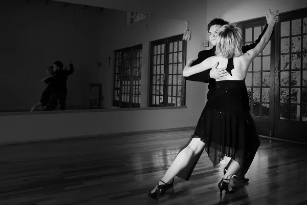 Un couple de jeunes adultes dansant et pratiquant la danse de salon ensemble dans un studio — Photo