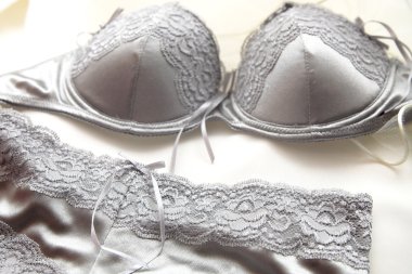 Gümüş dantel iç çamaşırı, sütyen ve külot bir yatakta yatarken çifti