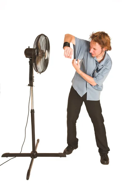 Человек в синей рубашке охлаждается перед вентилятором . — стоковое фото