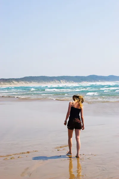 Blond kobieta spaceru na plaży, zbierając skorupy — Zdjęcie stockowe