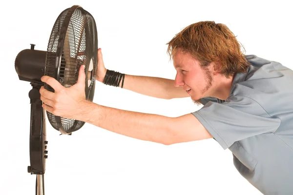 Hombre con camisa azul enfriándose delante de un ventilador . — Foto de Stock