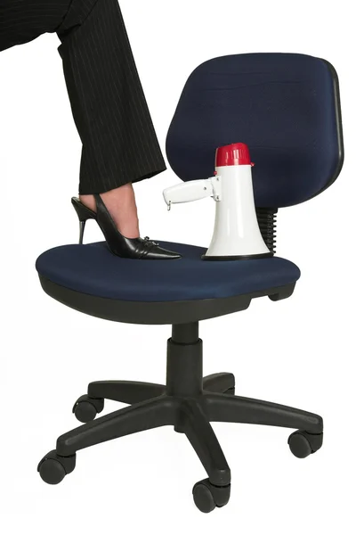 Voet van een vrouw en megafoon op een stoel van het Bureau. — Stockfoto