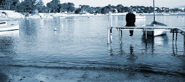 Una persona sentada en un muelle en Antibes, Francia —  Fotos de Stock