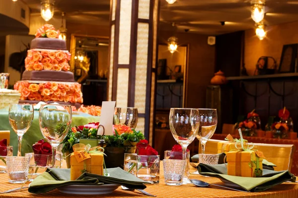 Tischdekoration mit Weingläsern und Kuchen im Hintergrund — Stockfoto