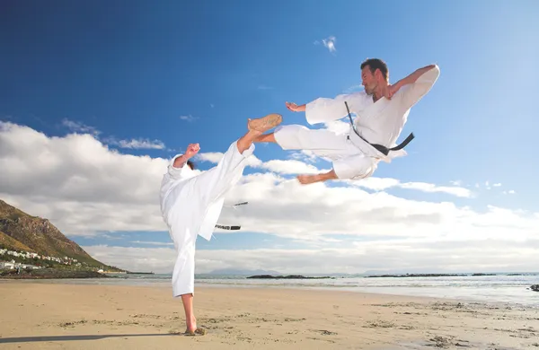 Young adult men with black belt practicing on the beach — Stock Photo, Image