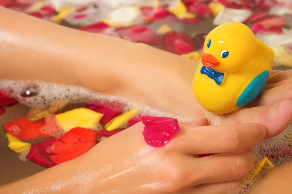 Canard jouet en plastique sur le pied d'une femme dans le bain . — Photo