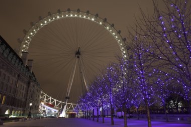 Christmas decorations in the trees with the London Eye in the background clipart
